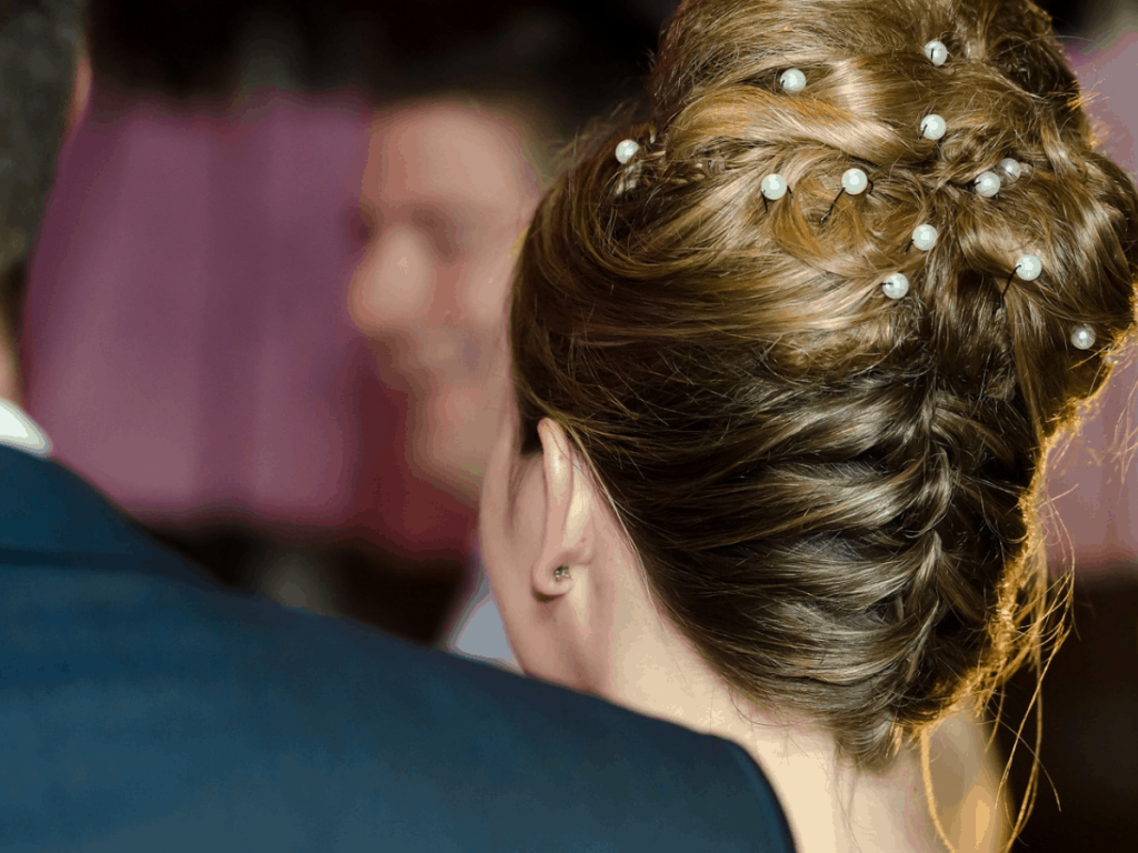 A woman with an updo hairstyle with jewelry in it.