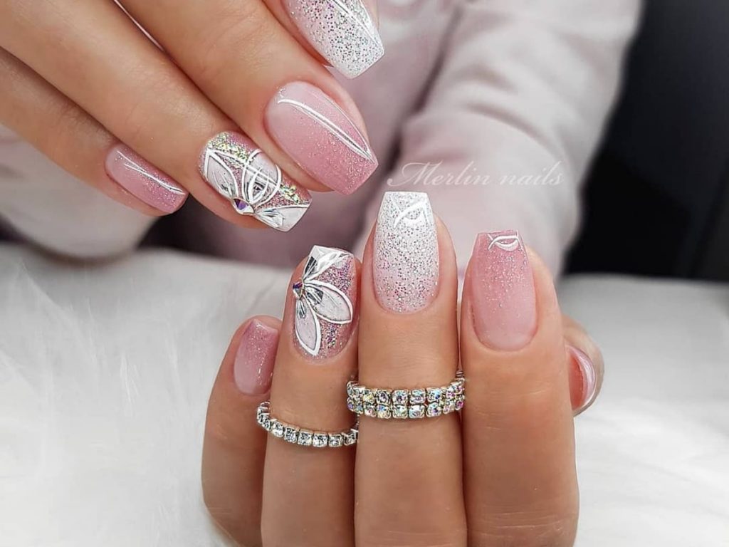 Light pink wedding nails with white accents matched with glitter and flower artwork.