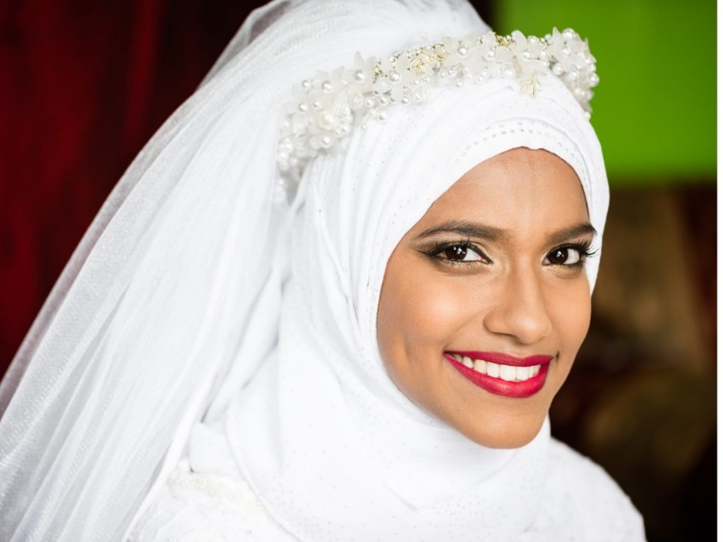 Muslim bride dressed in a white turban with flowers.  