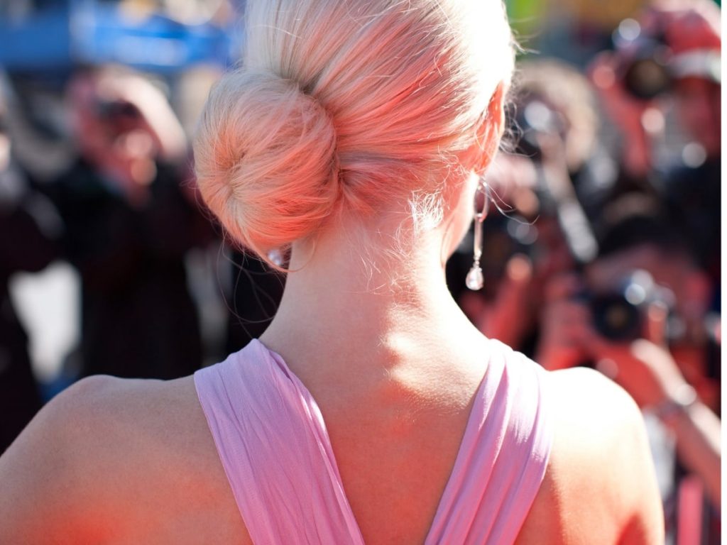 Blond haired woman showing the back of her hair styled in a side donut bun. 