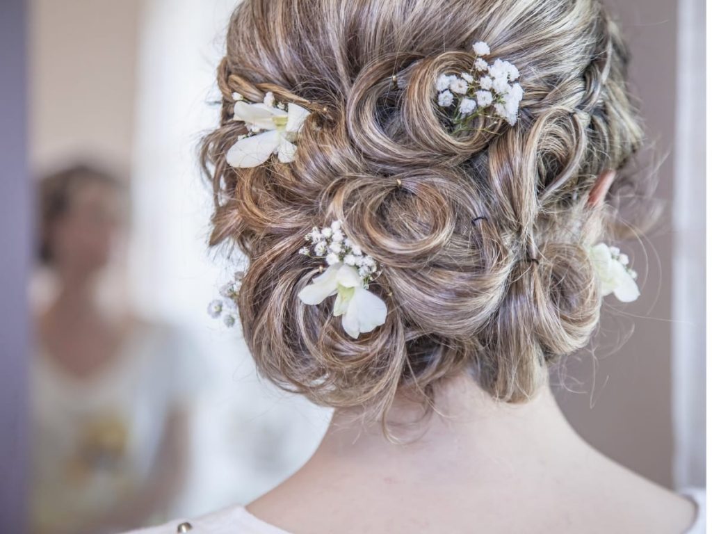 The back of a blond haired woman with a messy curl updo hairstyle.
