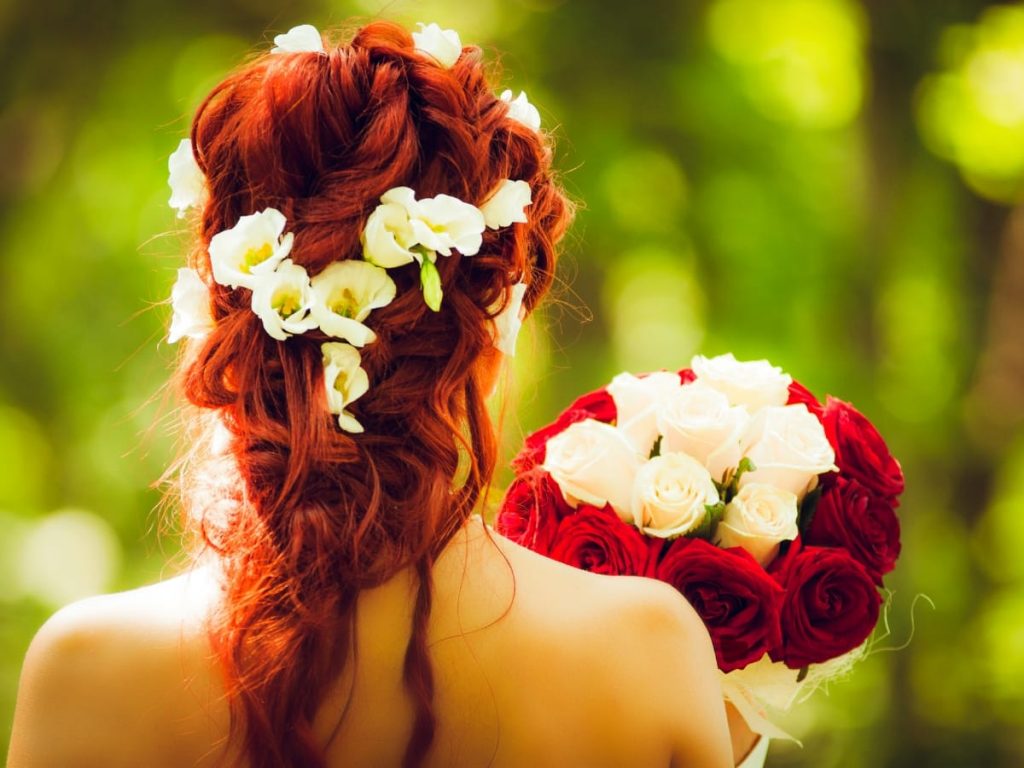 A picture of a woman wearing a messy spiral  hairstyle with rose accents