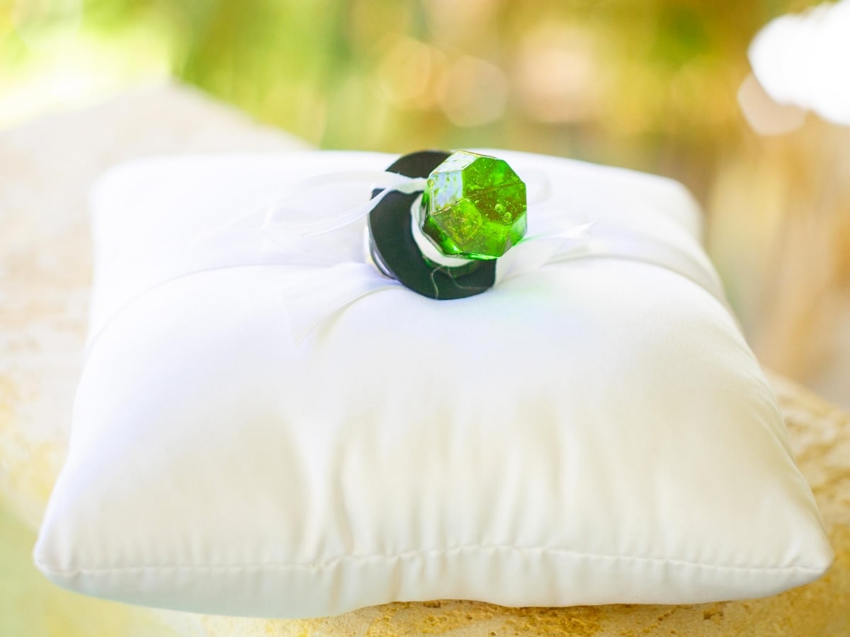 A ring pop candy ring placed on a pillow as a bridesmaid proposal idea.