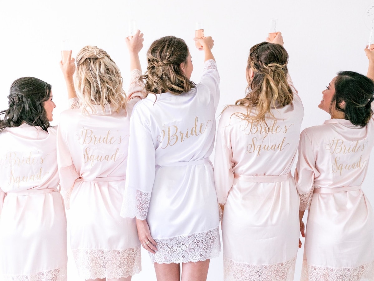 One bride and four bridesmaids turned away from the camera modeling their custom bridesmaid bathrobe gifts.