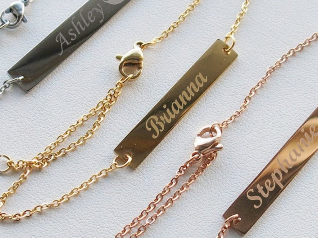 Three gold bar bracelets with bridesmaids names engraved on them.