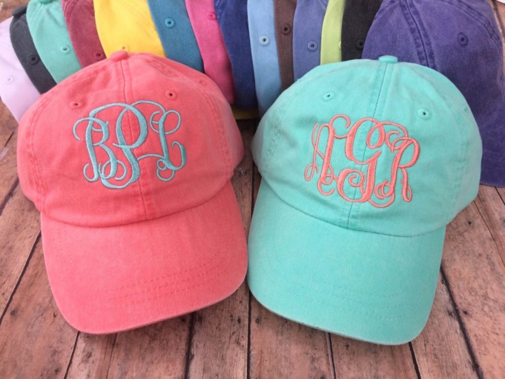 Two Hats that are embroidered with bride and bridesmaids initials.