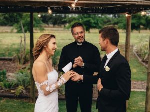 A couple facing each other in front of a pastor telling their vows to one another