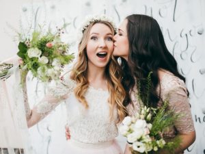 A bride being kissed on the cheek by maid of honor