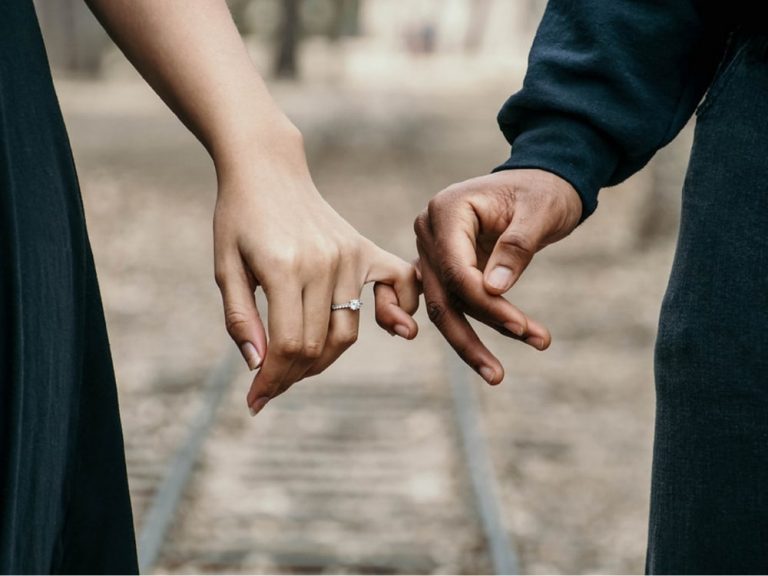 A close up of couples' hand holding each other with their pinky finger