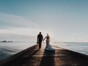 Couple walking into the sunset with the ocean facing them