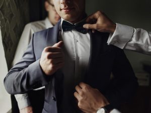 The groom wearing a tuxedo and helped by his groomsmen
