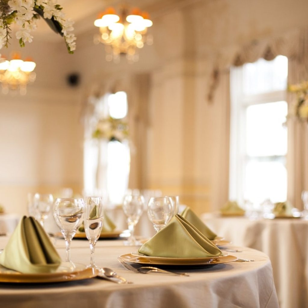 Tables at a fancy wedding venue that are prepped for dinner.