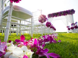 A outdoor wedding with the aisle decorated with fresh purple and pink flowers