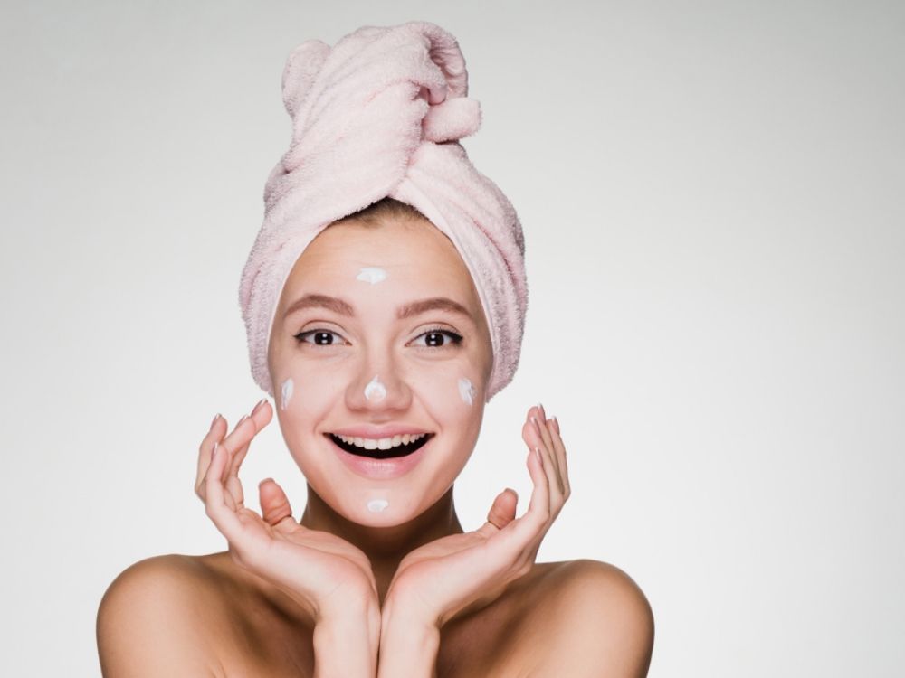 Woman with towel on head and doing skin care