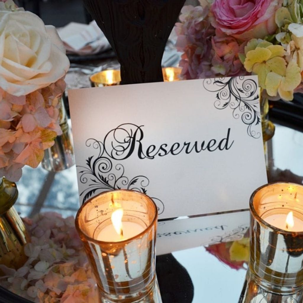 A card that reads reserved surrounded with flowers and candles