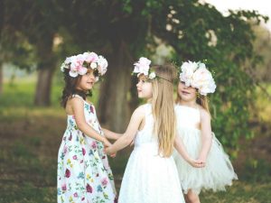 Three young girls with flower crowns holding hands and forming a circle
