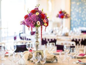 Reception tables with a tall centerpiece with colorful flowers on top