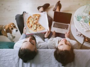 A couple lounging and eating pizza