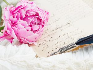 A handwritten wedding vow letter placed by a pink flower.